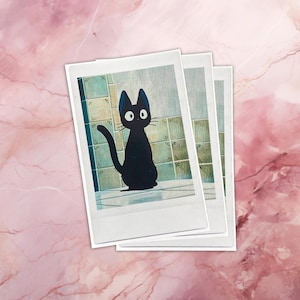 May include: Three instant photo prints of a black cat with large, round eyes sitting on a tiled floor. The cat is looking directly at the camera.