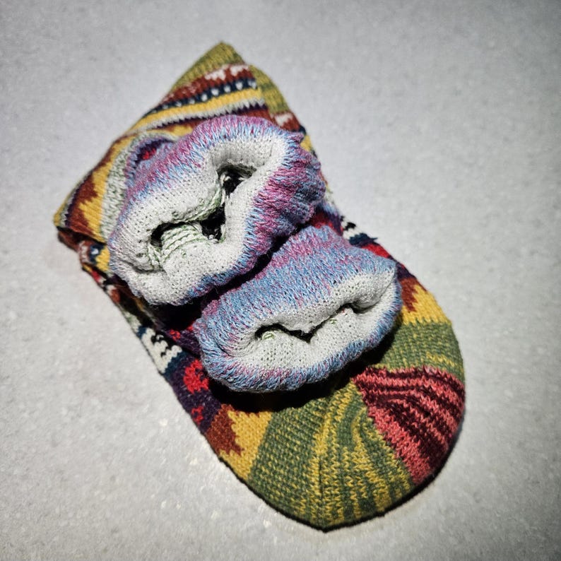 May include: A pair of colorful socks with a geometric pattern. The socks are folded and rolled up, showing the inside of the socks.