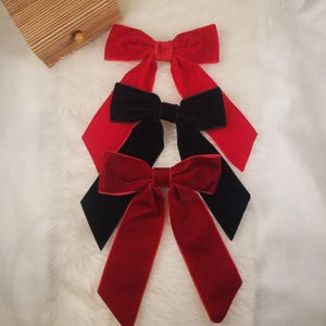 May include: Three velvet hair bows in red and black. The bows are tied in a knot and have long tails.