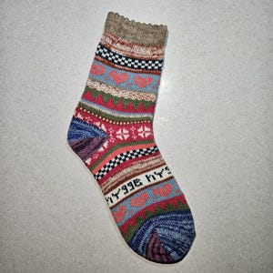 May include: A colorful patterned sock with a blue, red, green, and white design. The sock has a brown cuff and a pointed toe.