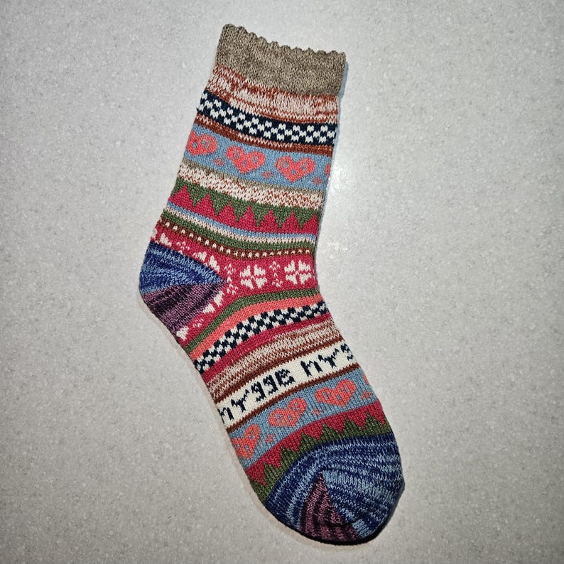 May include: A colorful patterned sock with a blue, red, green, and white design. The sock has a brown cuff and a pointed toe.
