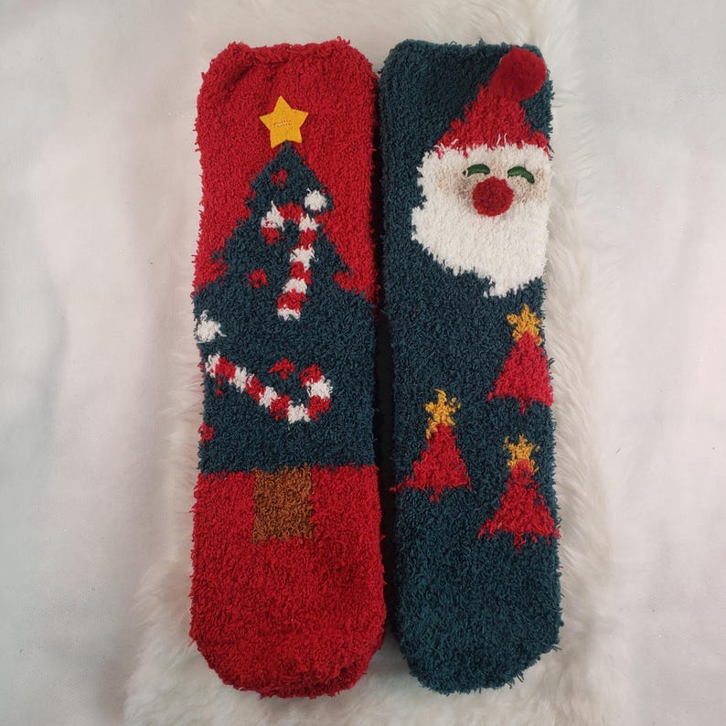 May include: A pair of fuzzy Christmas socks. One sock features a green Christmas tree with candy canes and a red background. The other sock features a white-bearded Santa Claus with a red hat and a green background.
