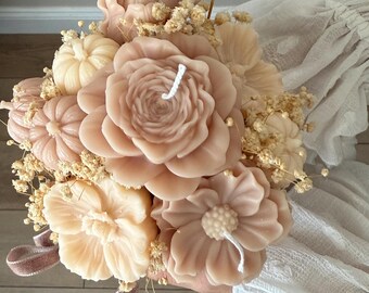 May include: A bouquet of beige wax candles shaped like various flowers and small pumpkins, accented with dried baby's breath flowers. The arrangement features multiple candle wicks protruding from the centers of the floral and pumpkin shapes.