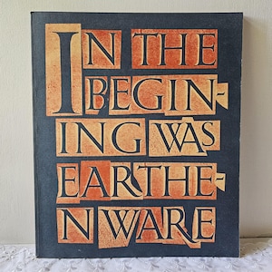 May include: A book cover with the words "IN THE BEGINNING WAS EARTHENWARE" in orange block letters against a dark blue background. The text is arranged in a stacked format, with each word or phrase on a separate line.