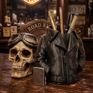 Puede incluir: Una calavera con gafas, un portalápices de chaqueta de cuero negro y un encendedor Harley-Davidson están sobre una barra de madera. El portalápices está lleno de bolígrafos y lápices. Un letrero de Harley-Davidson está en el fondo.