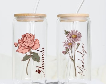 May include: Two glass can-shaped tumblers with bamboo lids and clear straws. The tumblers have floral designs and personalized names, "Amanda" and "Madelyn".