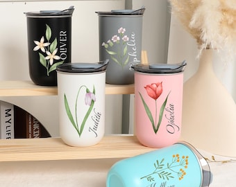May include: Five personalized stainless steel travel mugs with floral designs and names. The mugs are in different colors: black, gray, white, pink, and blue. The names on the mugs are Oliver, Ophelia, Judith, Ophelia, and Matthew.