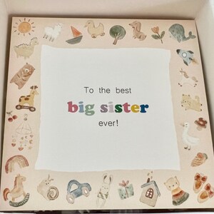 Może przedstawiać: Kartka z kolorową ramką z ilustracjami zwierząt i przedmiot&oacute;w. Na kartce napisano "To the best big sister ever!"
