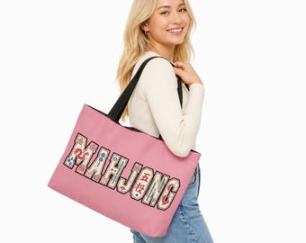 May include: A pink tote bag with black shoulder straps featuring the word MAHJONG in large, block-style letters. The letters are decorated with small, colorful illustrations of mahjong tiles, including dragons, flowers, and circles.