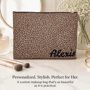 May include: A rectangular zippered makeup bag featuring a brown and black leopard print pattern. The name Alexis is embroidered in black script lettering on the lower right corner of the bag. The bag has a black zipper closure along the top edge.