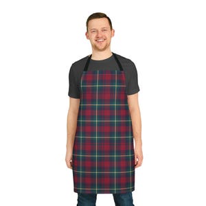 Könnte beinhalten: Eine rot, grün und gelb karierte Schürze. Die Schürze, getragen von einer Person, hat ein klassisches Tartanmuster. Sie hat einen Nackenriemen und Bindebänder. Der Stil ist traditionell, geeignet zum Kochen oder Basteln. Die Länge beträgt ca. 76 cm.