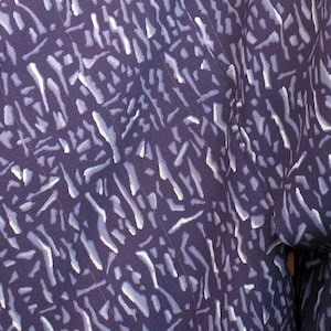 Puede incluir: Tela morada con un patr&oacute;n abstracto blanco de l&iacute;neas y rayas.