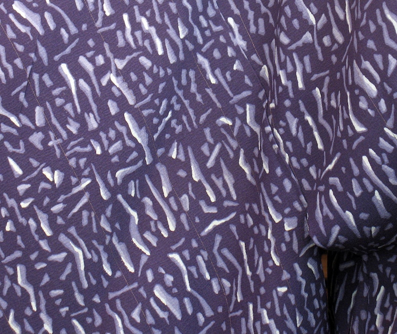 Puede incluir: Tela morada con un patr&oacute;n abstracto blanco de l&iacute;neas y rayas.