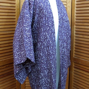 Puede incluir: Un kimono con estampado morado y blanco, con una abertura larga en la parte delantera y mangas anchas.