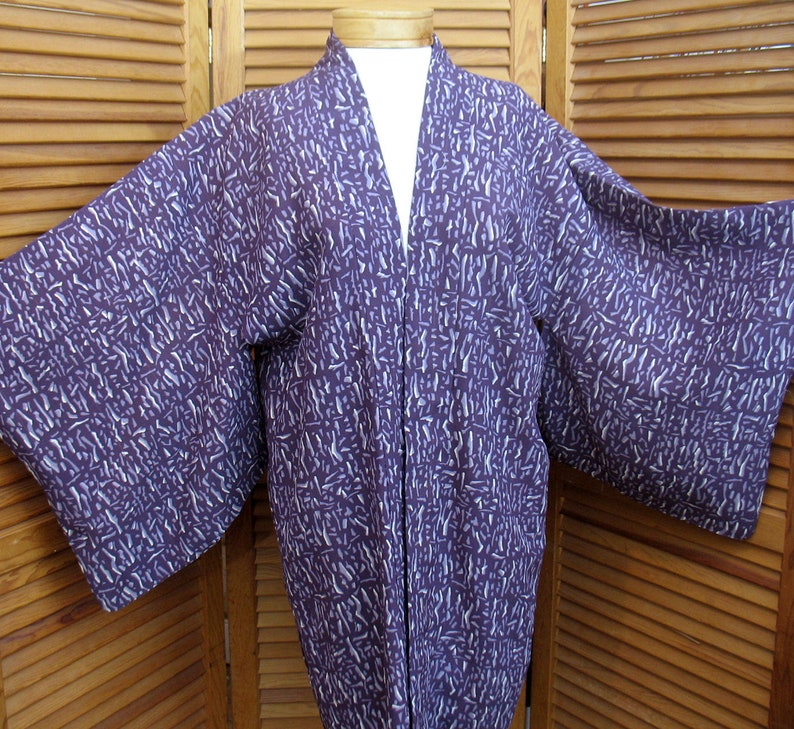 Puede incluir: Un kimono japon&eacute;s de manga larga con estampado morado y blanco. El kimono est&aacute; hecho de una tela suave y ligera y tiene un corte holgado.