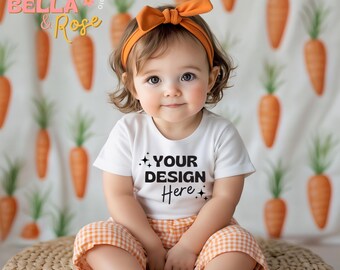 May include: A baby wearing a white t-shirt with the text "YOUR DESIGN Here" and orange gingham shorts. The baby has an orange bow headband. The background features a carrot pattern.