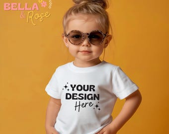May include: A young girl wearing a white t-shirt with the text "YOUR DESIGN Here" printed on it. She is wearing sunglasses and has her hair pulled back in a bun. The background is a solid yellow color.