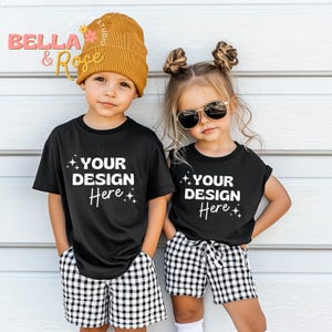 以下が含まれることがあります： 白い文字で「YOUR DESIGN Here」と書かれた黒いTシャツを着た子供2人。男の子は茶色のニット帽をかぶり、女の子はサングラスをかけています。2人とも黒と白のチェック柄のショートパンツを履いています。
