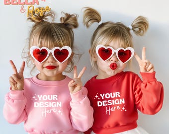 Puede incluir: Dos chicas con sudaderas rosas y rojas con el texto "Your Design Here" en ellas. Ambas llevan gafas en forma de corazón y tienen el pelo en coletas.