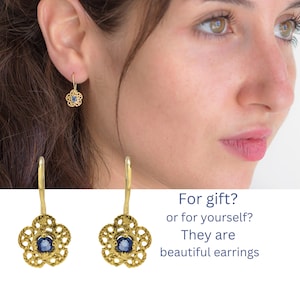 May include: Gold-colored filigree earrings with a flower design and a blue center stone. The earrings are displayed on a white background with the text: "For gift? or for yourself? They are beautiful earrings."