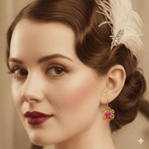 May include: A close-up of a woman wearing a gold filigree earring with a pink gemstone. The earring is a drop style with a floral design. The woman has dark hair styled in waves and is wearing dark red lipstick.
