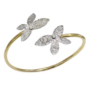 May include: A gold-toned cuff bracelet with two stylized flower designs. The flowers are silver-colored and encrusted with small, sparkling stones. The bracelet has a simple, elegant design, suitable for special occasions.