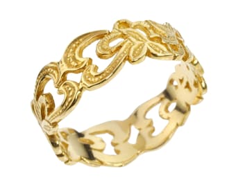May include: A gold-colored ring with an intricate, openwork design. The ring features a repeating pattern of swirling lines and floral elements. The ring is a band style, with a continuous pattern around the entire circumference.