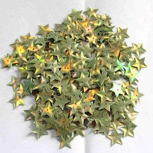 Pode incluir: Um grande monte de lantejoulas verdes iridescentes em forma de estrela. As lantejoulas têm um brilho metálico e são perfeitas para artesanato e decoração.