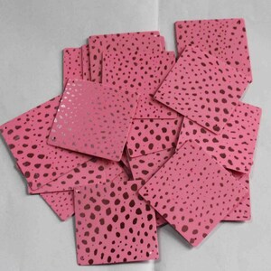 May include: A stack of pink square-shaped paper with a brown polka dot pattern.