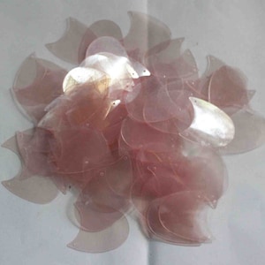 May include: A pile of pink iridescent plastic sequins in the shape of a crescent moon.