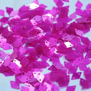Peut inclure: Un grand tas de paillettes iridescentes rose vif en forme de diamant.