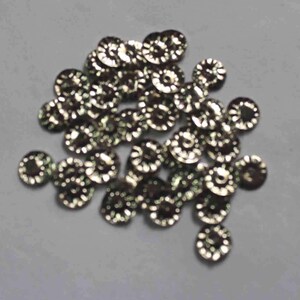 May include: A pile of silver-colored metal embellishments with a scalloped edge. The embellishments are round and have a raised center.