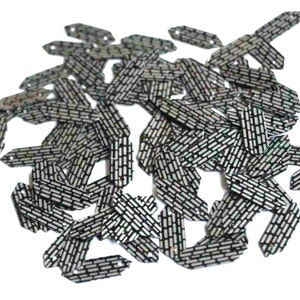 May include: A pile of black and silver sequins with a geometric pattern. The sequins are shaped like elongated hexagons with pointed ends.