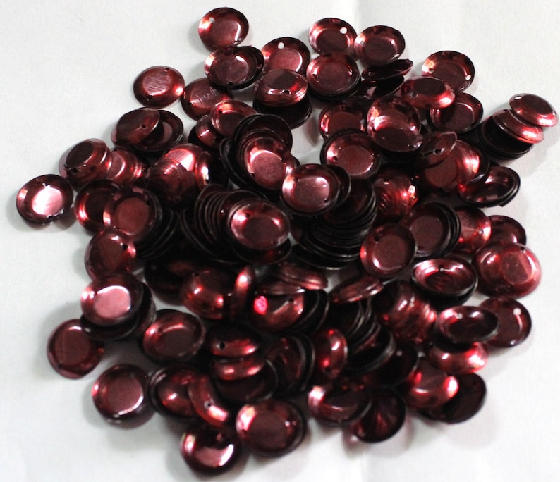 Puede incluir: Un mont&oacute;n grande de lentejuelas redondas de color marr&oacute;n. Las lentejuelas son brillantes y tienen un centro ligeramente elevado.