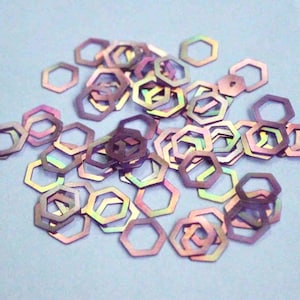 Op de afbeelding: Een strooiing van iriserende zeshoekige glitter, met een regenboog van kleuren, waaronder paars, roze en blauw.