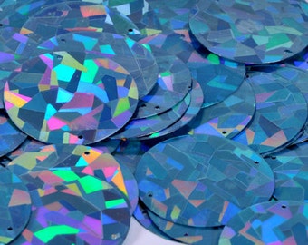 May include: A pile of iridescent blue sequins with a geometric pattern. The sequins are round and have a shiny finish.