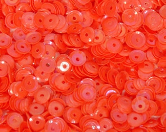 May include: A close-up view of a large quantity of bright orange sequins. The sequins are round with a hole in the centre. They are perfect for crafting and sewing projects.