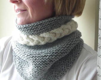 May include: A gray and white knitted cowl neck scarf with a braided design.