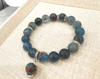 May include: A blue and brown gemstone bracelet with a matching pendant. The bracelet is made of round beads and has silver accents.
