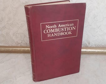 May include: A maroon hardcover book titled "North American Combustion Handbook" in a white rectangular box. The book is standing upright, with the title clearly visible. The book's spine has text running vertically.
