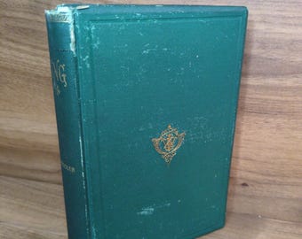 May include: A hardcover book with a dark green cloth cover featuring a gold embossed emblem on the front. The spine shows partial gold lettering and visible wear along the edges. The book is standing upright, displaying its front cover and spine.