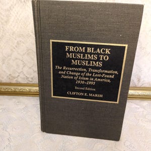 May include: A hardcover book titled "FROM BLACK MUSLIMS TO MUSLIMS" with gold lettering on a black rectangular label. The book's cover is a dark gray color. The text below the title reads "The Resurrection, Transformation, and Change of the Lost-Found Nation of Islam in America, 1930-1995".