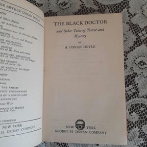 K&ouml;nnte beinhalten: Aufgeschlagenes Buch mit dem Titel "THE BLACK DOCTOR and Other Tales of Terror and Mystery" von A. Conan Doyle. Ver&ouml;ffentlicht von George H. Doran Company, New York. Die Titelseite ist zu sehen.