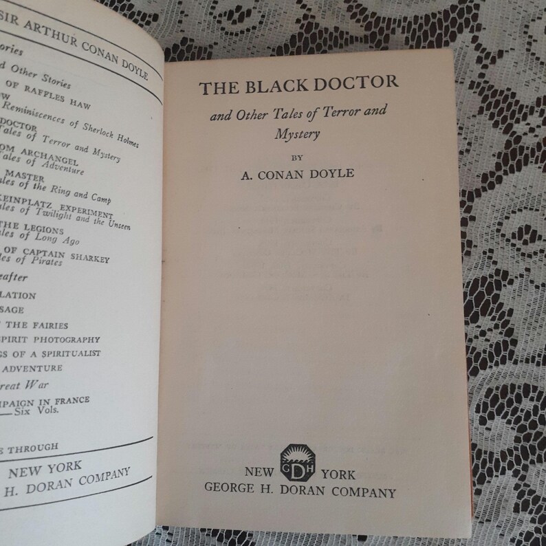 K&ouml;nnte beinhalten: Aufgeschlagenes Buch mit dem Titel "THE BLACK DOCTOR and Other Tales of Terror and Mystery" von A. Conan Doyle. Ver&ouml;ffentlicht von George H. Doran Company, New York. Die Titelseite ist zu sehen.