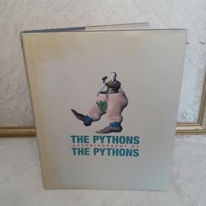 May include: A book titled "The Pythons Autobiography by The Pythons" with a cover image of a man in a pink pair of pants with a green leaf design and a man's head and torso sticking out of the pants.