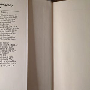 May include: An open book with text on the left page and a blank right page. The book is a "Book Club Edition". The pages are off-white, and the spine is light grey. The book is on a wooden surface.