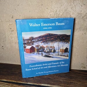 May include: A hardcover book titled Walter Emerson Baum 1884-1956, Pennsylvania Artist and Founder of the Baum School of Art and Allentown Art Museum by Martha Young Hutson-Saxton, featuring a blue cover with a winter landscape painting.