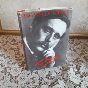 May include: A vintage hardcover book titled "H.G. Wells in Love" with a black and white photo of H.G. Wells on the cover. The book has a red spine and a red signature on the cover that reads "H.G. Wells".
