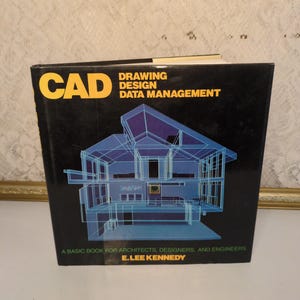 May include: A book titled "CAD Drawing Design Data Management" with a blue architectural illustration on the cover. The book is black with yellow and white text. The author's name, E. Lee Kennedy, is printed at the bottom.