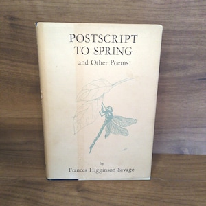 May include: A vintage book titled "Postscript to Spring and Other Poems" by Frances Higginson Savage. The cover is a light beige with a green illustration of a dragonfly and leaves. The book is standing upright on a wooden surface.